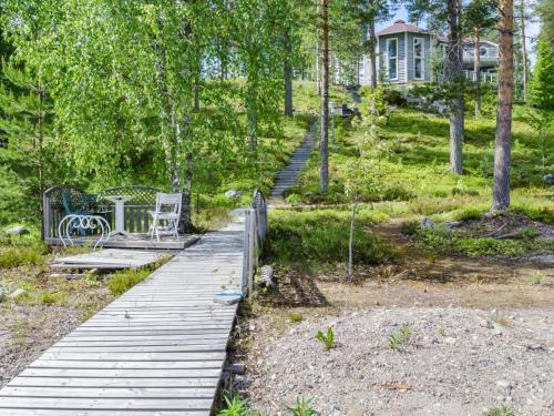 einen hölzernen Gehweg mit einem Tisch und Stühlen darauf in der Unterkunft Holiday Home Huvila lomaonni by Interhome in Kolinkylä