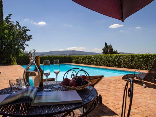 een tafel met wijnglazen en een fruitschaal naast een zwembad bij Holiday Home Vedi Torre by Interhome in San Gimignano
