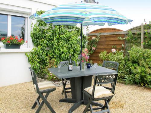 une table noire avec un parasol et deux chaises dans l'établissement Holiday Home Penn Ar Bed by Interhome, à Pleubian