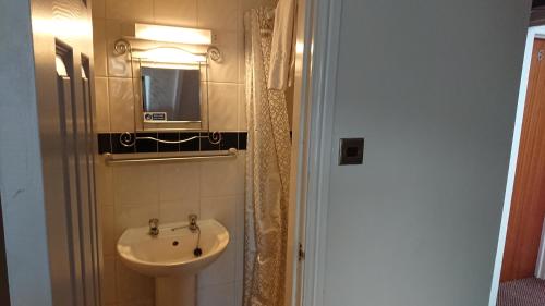 ein Bad mit einem Waschbecken und einem Spiegel in der Unterkunft Ash Lea Hotel in Blackpool