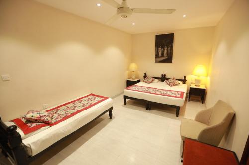 a bedroom with two beds and a chair in it at Earl's Red Kurunegala in Kurunegala