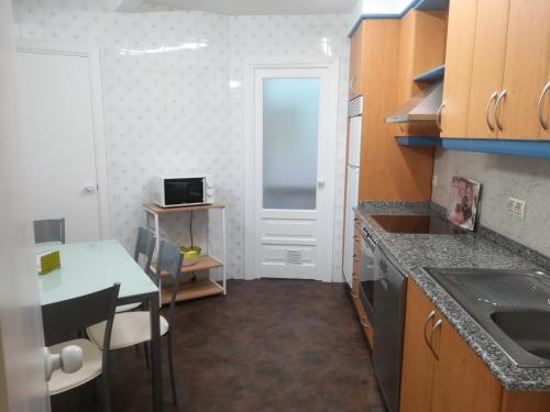 una pequeña cocina con mesa y puerta en PISO XUNQUEIRA, en Viveiro