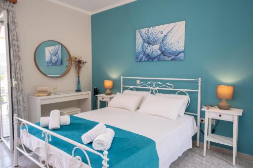 a blue bedroom with a bed with towels on it at Pavlatos Apartments & Studios in Sami