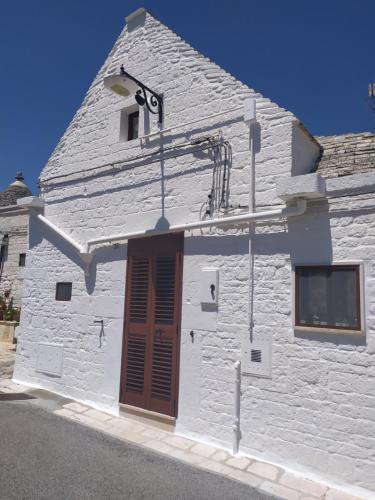 een wit gebouw met een bruine deur erop bij Trullo Girolamo in Alberobello