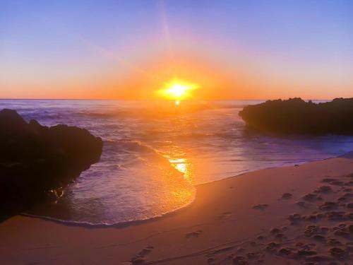 a sunset over the ocean with a sandy beach at Ocean Reef Vista in Perth