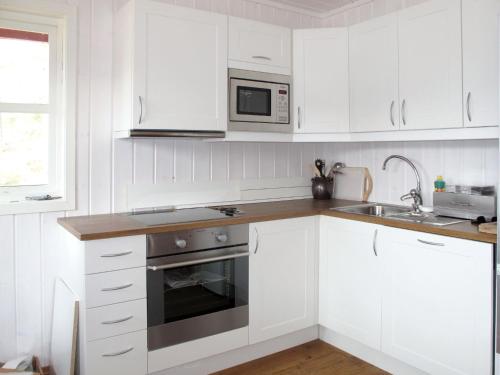 een keuken met witte kasten en een roestvrijstalen oven bij Chalet Risdalbu - SOO021 by Interhome in Mjåvatn