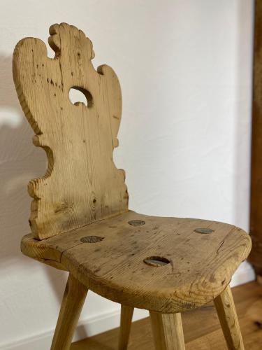 a wooden chair sitting in front of a wall at Ferienwohnung Dolomiten in Nußdorf