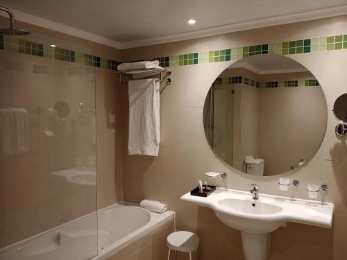 a bathroom with a sink and a tub and a mirror at Occidental Sousse Marhaba in Sousse