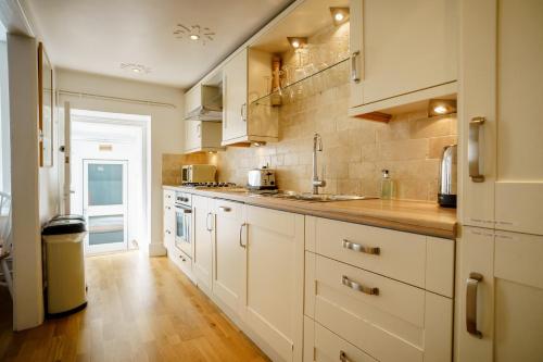 a kitchen with white cabinets and a wooden floor at Central Courtyard Apartment in Bath