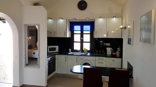 a kitchen with white cabinets and a table and a window at Caleta Holiday Bungalow in Caleta De Fuste