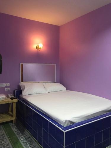 a bed in a room with a purple wall at เจิดจรัสรีสอร์ทโรงแรม24ชม in Chon Buri