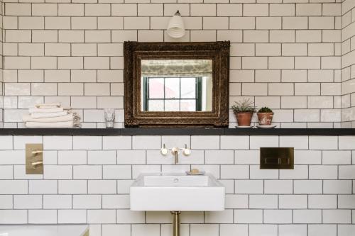 a white bathroom with a sink and a mirror at The Bull Inn in Totnes