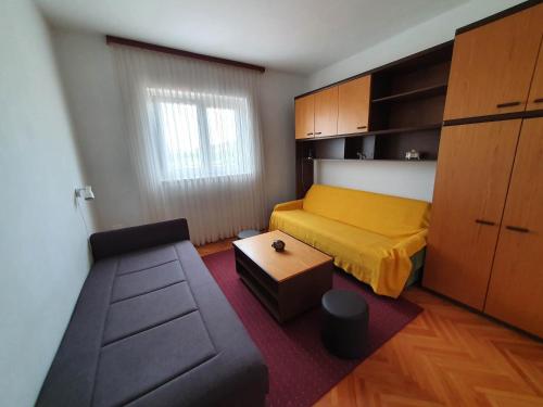 a small bedroom with a yellow bed and a couch at Island Murter in Betina