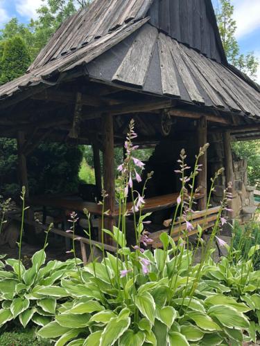 a wooden gazebo in a garden with flowers at Rysiówka in Poronin