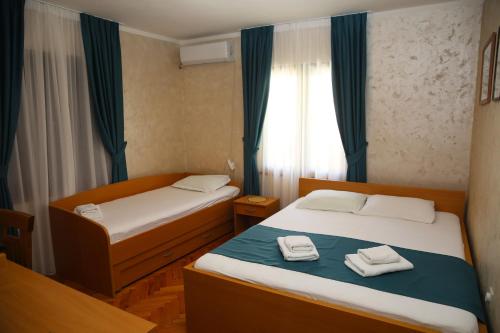 two beds in a small room with a window at Apartments Jovanovic - Alkima in Kotor