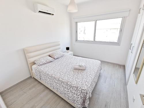 a white bedroom with a bed and a window at Mackenzie Seaview Paradise in Larnaka