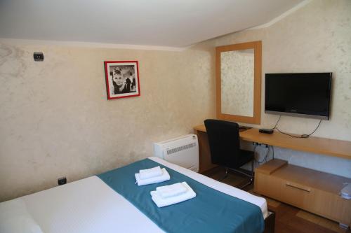 a hotel room with a bed and a desk and a television at Apartments Jovanovic - Alkima in Kotor