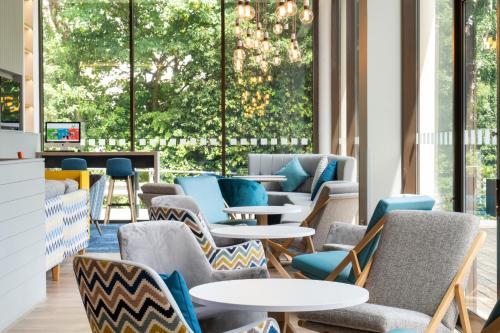 a waiting room with tables and chairs and large windows at Holiday Inn Bournemouth by IHG in Bournemouth