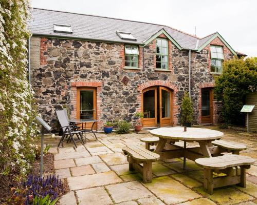 利馬瓦迪的住宿－Ballyhenry House and Apartments，石头建筑前的庭院配有桌子和长凳