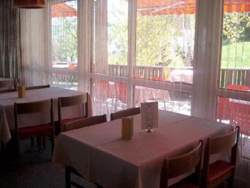 a dining room with two tables and a large window at Hotel Restaurant Cristal in Braunwald