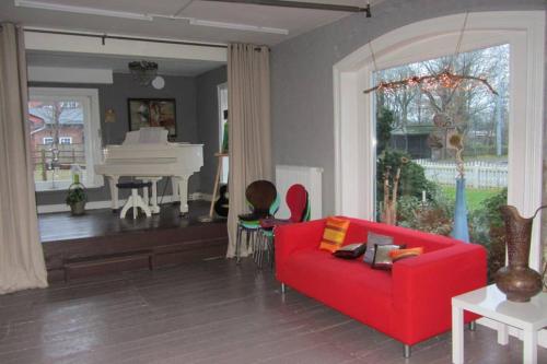 a living room with a red couch and a piano at Grosses und gemütliches Landhaus in Sankt Margarethen