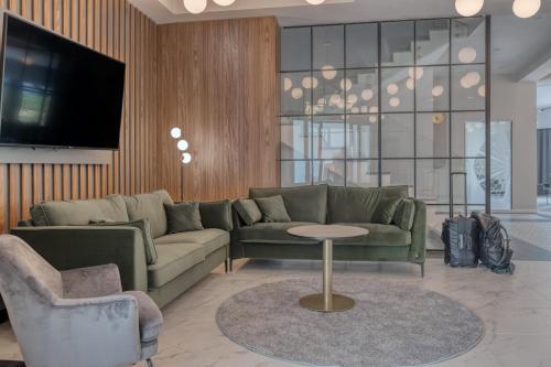 a living room with a couch and a table and a tv at Sudecki Resort & SPA in Karpacz