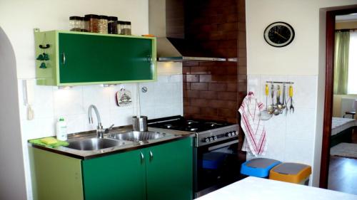 - une cuisine avec des placards verts, un évier et une cuisinière dans l'établissement Apartament Laura, à Władysławowo