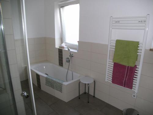baño con bañera, ventana y taburete en Ferienhaus Kettler II, en Muhr amSee