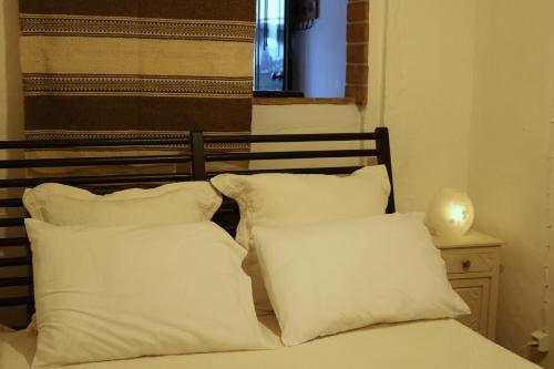 1 cama con almohadas blancas junto a una ventana en Casa do Compadre - Casas de Taipa, en São Pedro do Corval
