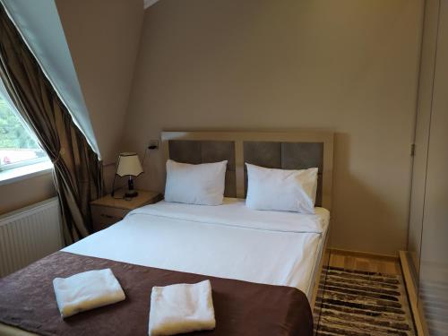 a bedroom with a bed with white sheets and pillows at Gold Hotel Quba in Quba