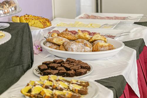Una mesa cubierta con platos de pasteles y postres. en Hotel Majestic, en Bellaria-Igea Marina