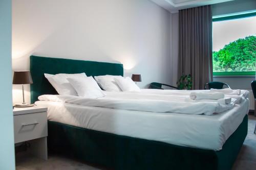 a bedroom with a large bed with a green headboard at Hotel Promenada Biznes & Wypoczynek in Radom