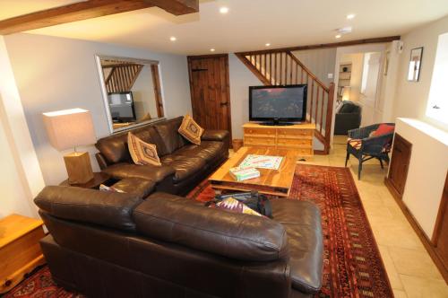 a living room with a leather couch and a television at Church Cottage in Charmouth
