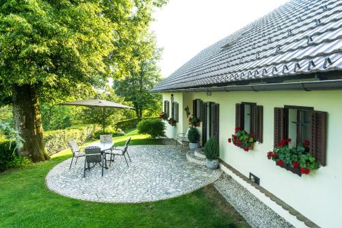 eine Terrasse mit einem Tisch und Stühlen neben einem Haus in der Unterkunft Holiday House in Nature with Pool, Pr Matažič in Kamnik