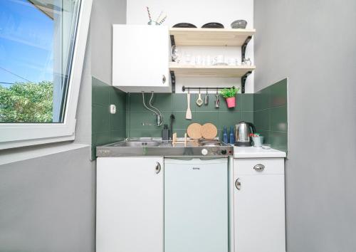 a small kitchen with white cabinets and a sink at Frida Rooms and Apartments Vodice in Vodice