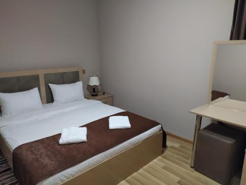 a bedroom with a bed with two towels on it at Gold Hotel Quba in Quba