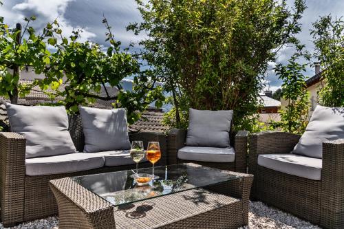 a patio with wicker chairs and a table with wine glasses at Hotel Villa Mayr Rooms & Suites in Brixen