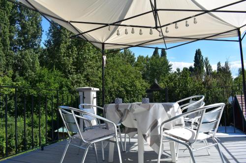 a table and chairs under a white umbrella on a deck at Sziget Vendégház in Szigliget