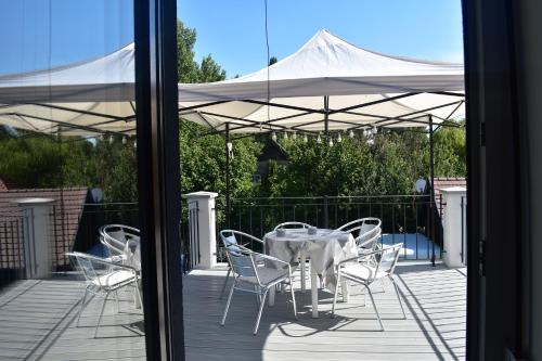 a table and chairs on a deck with an umbrella at Sziget Vendégház in Szigliget
