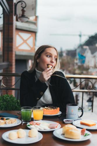 a woman sitting at a table eating food at Hotel Fioreze Centro in Gramado
