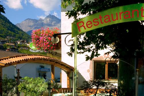 a restaurant sign in front of a building with flowers at Gasthof Anny in Marlengo