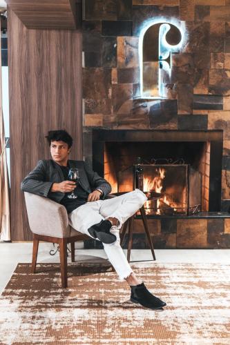 a man sitting in a chair in front of a fireplace at Hotel Fioreze Centro in Gramado