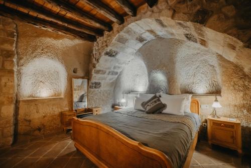 um quarto com uma cama num quarto de pedra em Dere Suites Cappadocia em Ürgüp