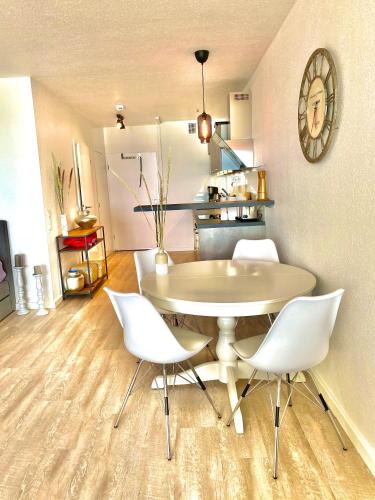 a dining room with a table and white chairs at Studio mit Panorama-Meerblick und direkter Strandlage in Scharbeutz in Scharbeutz