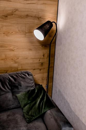 a lamp in the corner of a room with a couch at Апартаменти затишні в центрі Чорткова in Chortkiv