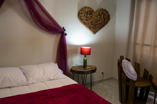 a bedroom with a bed and a heart on the wall at Pousada Rua de Lazer in Domingos Martins