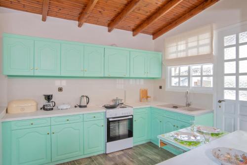 a kitchen with mint green cabinets and a table at Villa Magnolia in Nafplio