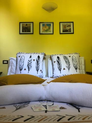 a bed with white pillows and a yellow wall at Notti Etrusche a Sovana in Sovana
