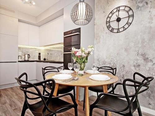 a dining room with a table and chairs and a clock at City Center - Granary Island by Apartmore in Gdańsk