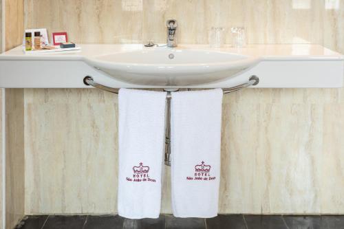 a bathroom with two white towels hanging from a sink at Hotel Sao Joao De Deus by RIDAN Hotels in Elvas